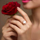 Eleganter 18k Gelbgold-Ring mit Kleeblatt-Motiv aus weißem Perlmutt, getragen an einer Hand, die eine rote Rose hält; romantische Schmuckfotografie mit luxuriösem, zeitlosem Design.