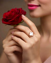 Eleganter 18k Gelbgold-Ring mit Kleeblatt-Motiv aus weißem Perlmutt, getragen an einer Hand, die eine rote Rose hält; romantische Schmuckfotografie mit luxuriösem, zeitlosem Design.