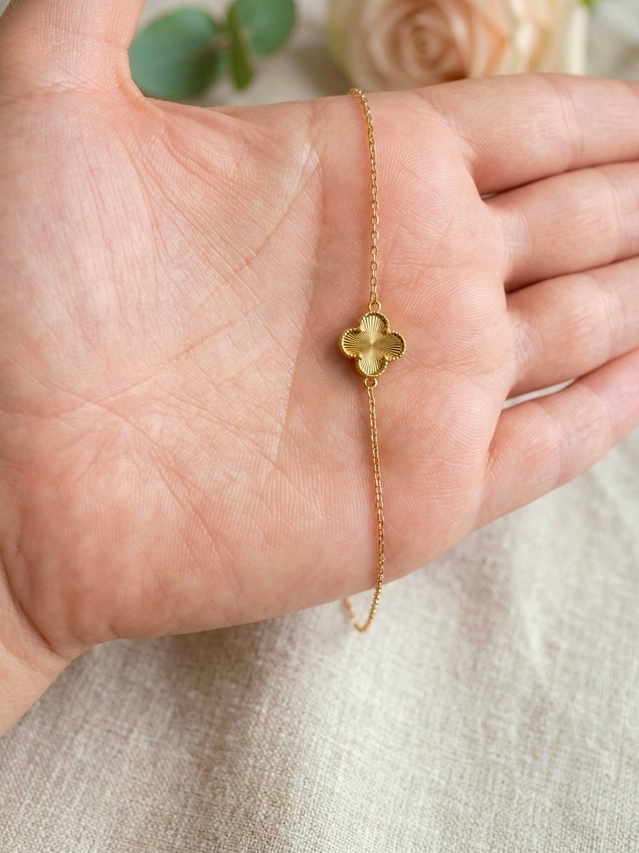 Filigranes Armband aus 18 Karat Gelbgold mit strukturiertem Kleeblatt-Motiv auf einer Handfläche.