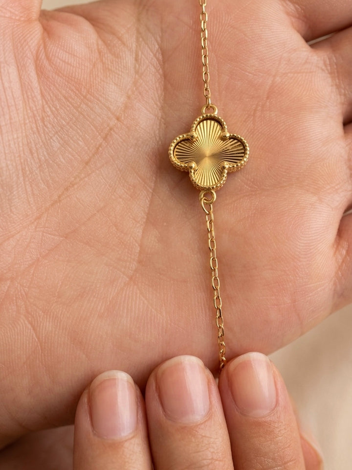 Detailaufnahme eines filigranen Armbands aus 18 Karat Gelbgold mit fein strukturiertem Kleeblatt-Motiv und Goldkügelchen-Bordüre.