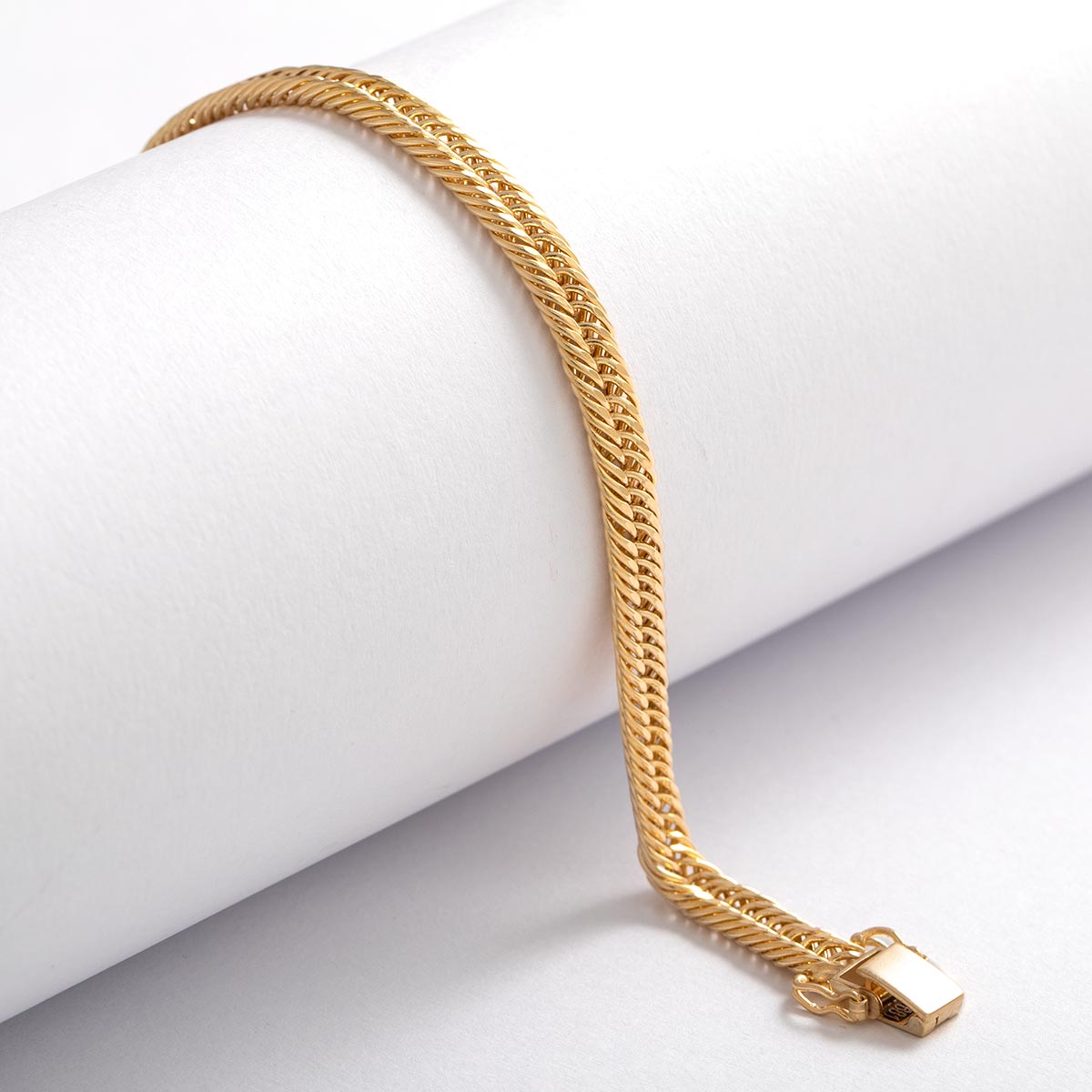 Armband aus 18 Karat Gelbgold mit fein gewebter, flach anliegender Struktur und polierter Oberfläche, dekorativ um eine weiße Rolle drapiert, mit rechteckigem Sicherheitsverschluss.