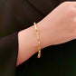 Armband aus 18 Karat Gelbgold mit geometrischem Gliederdesign und dezentem Muster, elegant am Handgelenk getragen und kombiniert mit einem schwarzen Outfit.