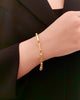 Armband aus 18 Karat Gelbgold mit geometrischem Gliederdesign und dezentem Muster, elegant am Handgelenk getragen und kombiniert mit einem schwarzen Outfit.