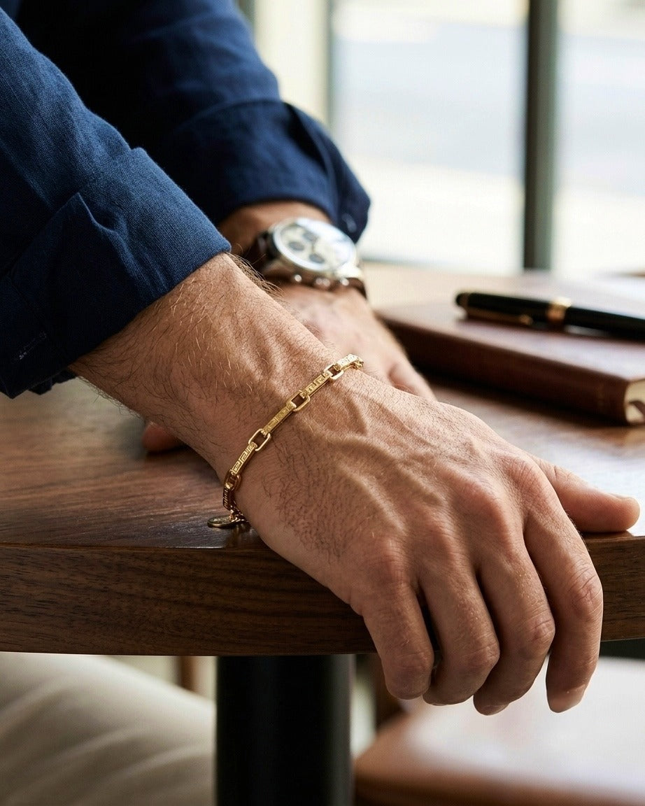 Hochwertiges 18 Karat Goldarmband mit länglichen Gliedern und griechischem Mäander-Muster am Handgelenk getragen. Eleganter Gelbgoldschmuck für Damen und Herren – zeitlos, stilvoll und vielseitig kombinierbar.