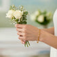 Elegantes Damenarmband aus 18k Gelbgold am Handgelenk, getragen von einer Frau mit weißem Rosenstrauß – zeitloser Goldschmuck, feminin, edel und stilvoll.