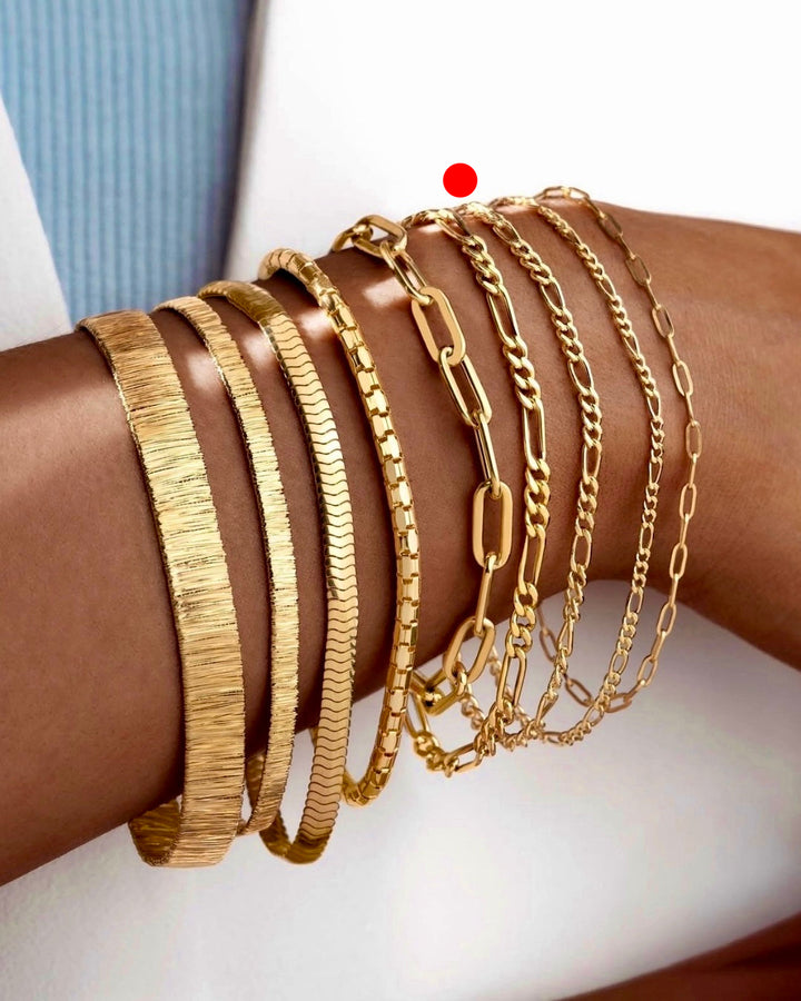 Modell trägt mehrere 18 Karat Goldarmbänder in verschiedenen Kettenarten im Layering-Look, hochwertiger handgefertigter Goldschmuck stilvoll kombiniert am Handgelenk.
