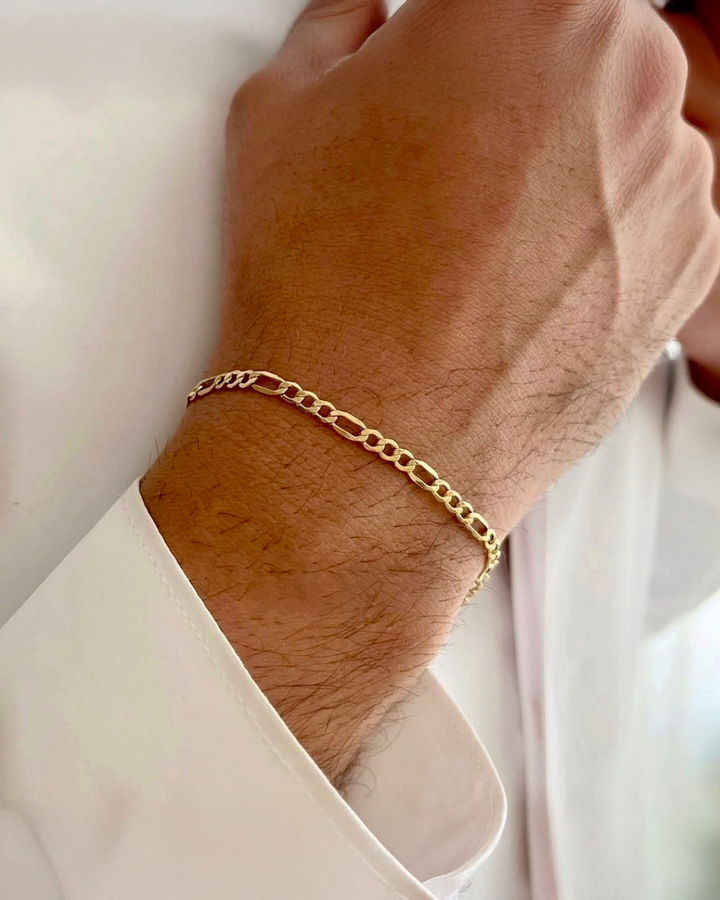 18 Karat Gelbgold-Figaro-Armband am Handgelenk getragen – eleganter, zeitloser Goldschmuck aus massivem 18k Gold, hochwertig verarbeitet und stilvoll kombiniert.