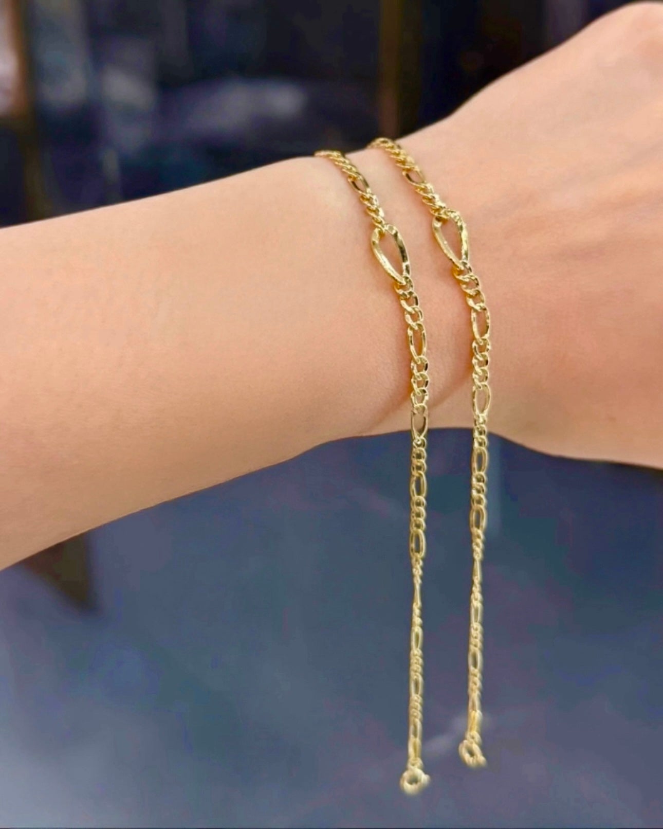 18k Gelbgold-Armband im Figaro-Design, doppelt um das Handgelenk gelegt. Feine, längliche und runde Glieder reflektieren das Licht und sorgen für einen eleganten, glänzenden Look.