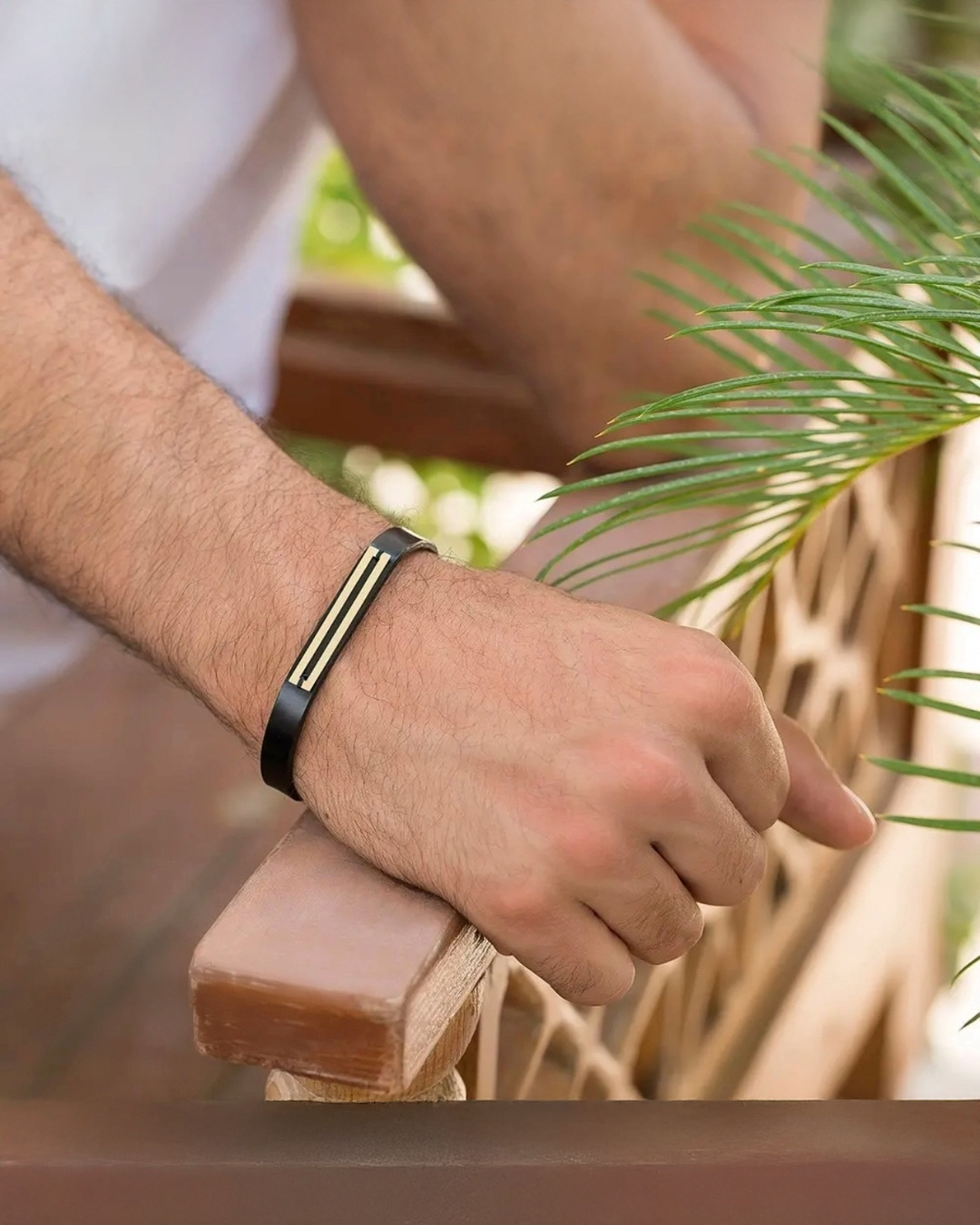 Lederarmband mit Goldverzierung am Handgelenk eines Mannes getragen – elegant, maskulin &amp; zeitlos.