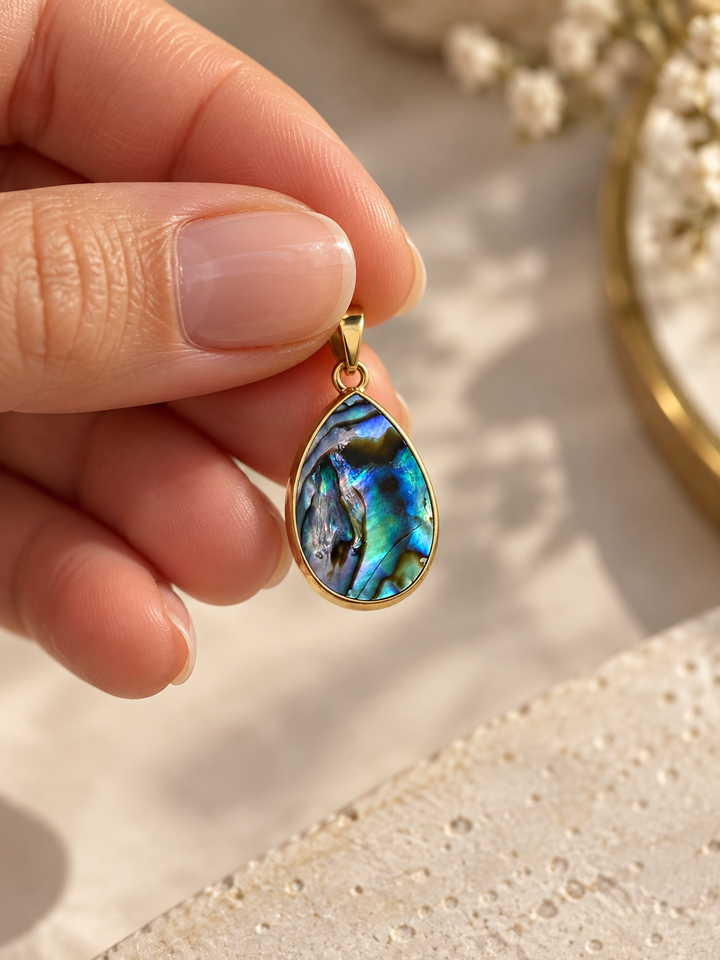 Rangin Kaman Anhänger aus 18k Gelbgold mit blau-grünem Schmuckstein in der Hand gehalten