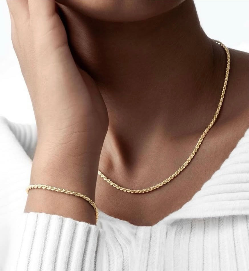 Ensemble aus 18k Gold im Kordeldesign – Halskette und Armband Tanab-e Tala, getragen in harmonischer Kombination auf heller Kleidung.