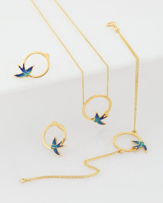 18k Gold Schmuckset mit Schwalbendesign – Halskette, Armband & Ohrstecker aus Gelbgold mit blauer Emaille, freigestelltes Produktbild.