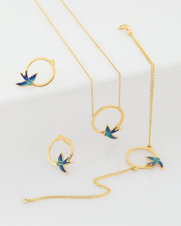 18k Gold Schmuckset mit Schwalbendesign – Halskette, Armband &amp; Ohrstecker aus Gelbgold mit blauer Emaille, freigestelltes Produktbild.