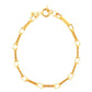 Elegant gekleideter Mann in einem dunkelblauen Anzug trägt eine goldene Halskette und ein passendes Armband aus 18 Karat Gelbgold. Der Look wirkt luxuriös, selbstbewusst und zeitlos – aufgenommen in einem stilvollen Raum mit Bücherregal im Hintergrund.