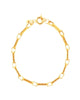 Elegant gekleideter Mann in einem dunkelblauen Anzug trägt eine goldene Halskette und ein passendes Armband aus 18 Karat Gelbgold. Der Look wirkt luxuriös, selbstbewusst und zeitlos – aufgenommen in einem stilvollen Raum mit Bücherregal im Hintergrund.