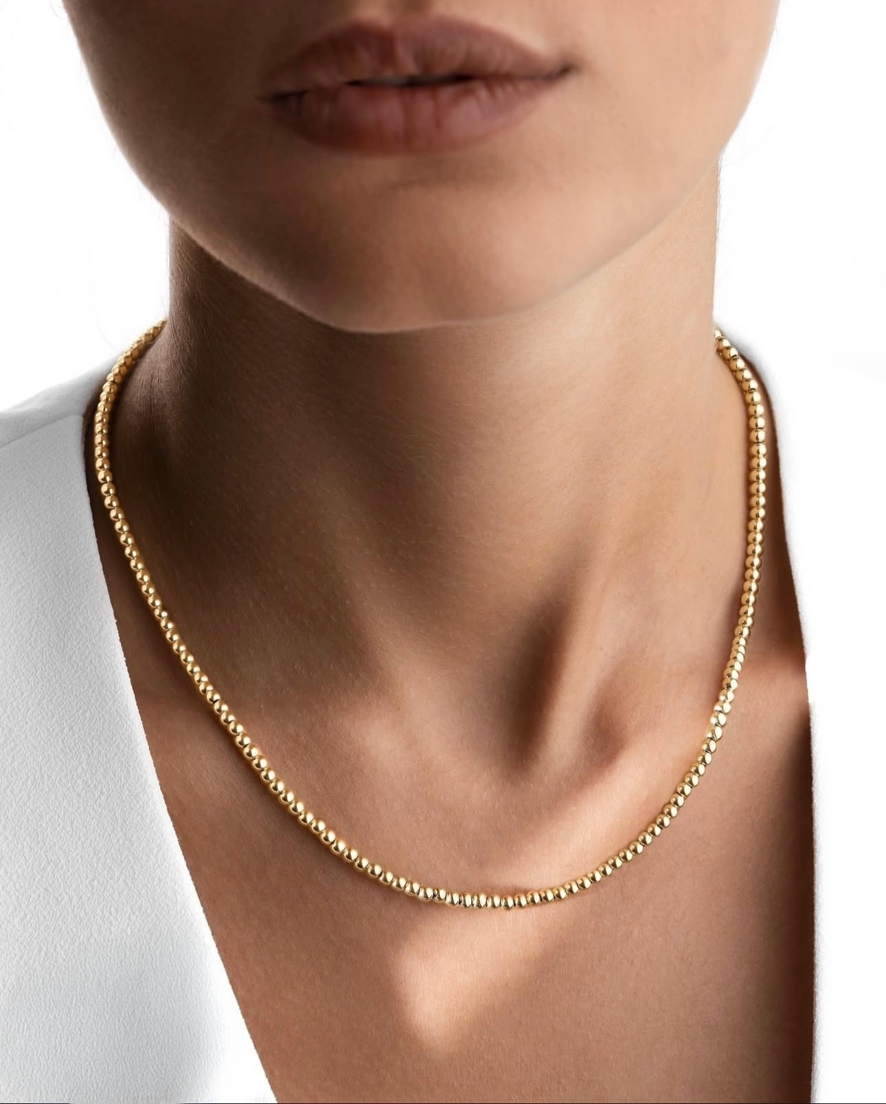 Goldene Perlenkette aus 18k – Morvarid-e Gardan, elegant am Hals getragen, zart glänzend zur weissen Bluse