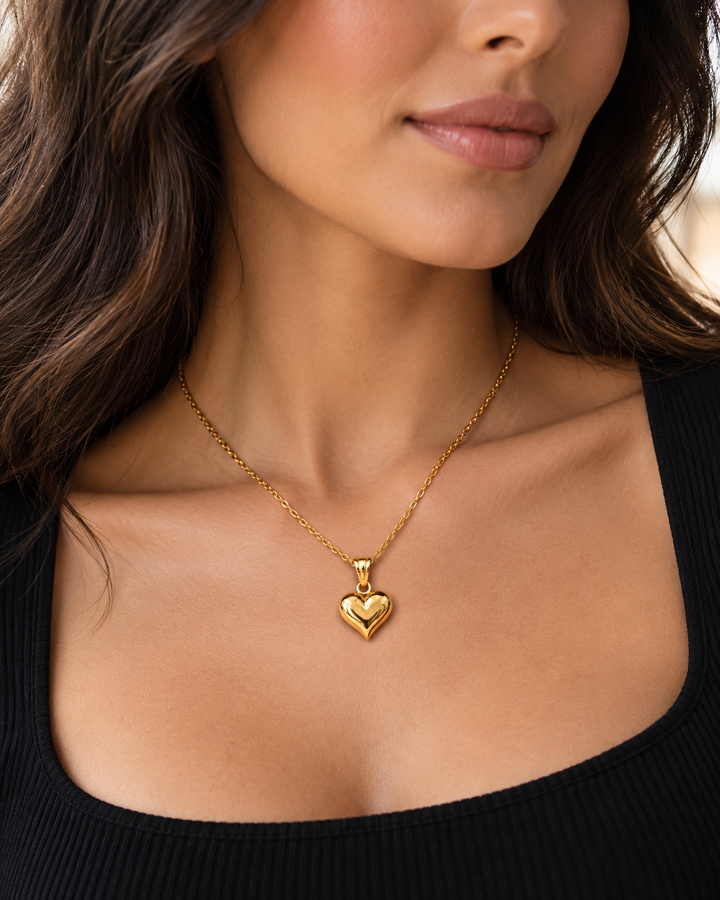 Model trägt eine 42,5 cm lange Halskette aus 18 Karat Gelbgold (750) mit glänzendem Herzanhänger, 1,4 cm breit, elegant kombiniert mit schwarzem Oberteil.