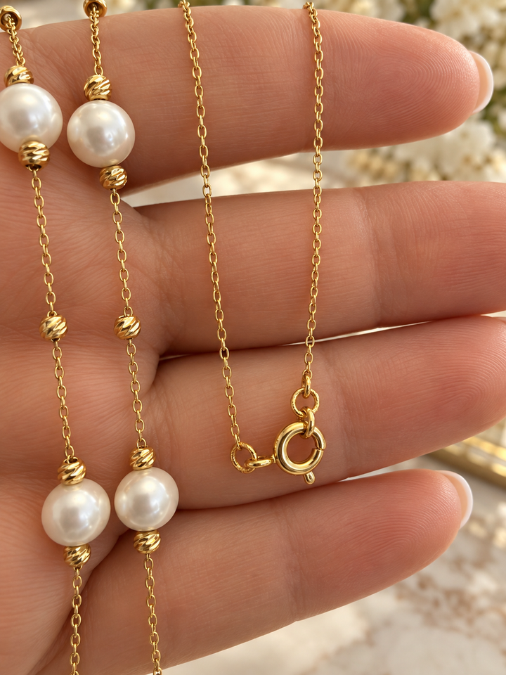 Nahaufnahme der Gelbgold-Halskette mit 6 mm Perlen, strukturierten Goldkügelchen und Federringverschluss.
