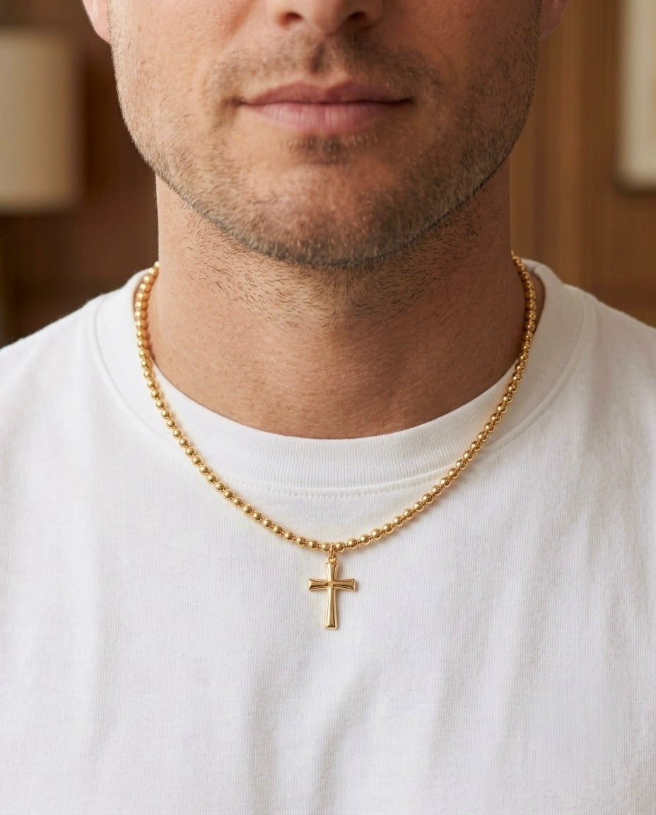 Herren-Halskette aus 18 Karat Gelbgold mit Kugelkette und schlichtem Kreuzanhänger, getragen zu einem weissen T-Shirt – zeitloser christlicher Goldschmuck für Herren.