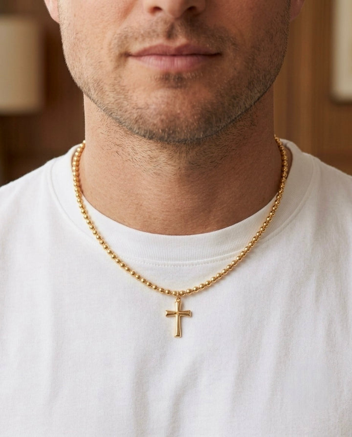 Herren-Halskette aus 18 Karat Gelbgold mit Kugelkette und schlichtem Kreuzanhänger, getragen zu einem weissen T-Shirt – zeitloser christlicher Goldschmuck für Herren.