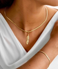 Zanjir-e Mari mit goldener Feder, getragen mit passendem Armreif – eleganter Look auf weißem Oberteil