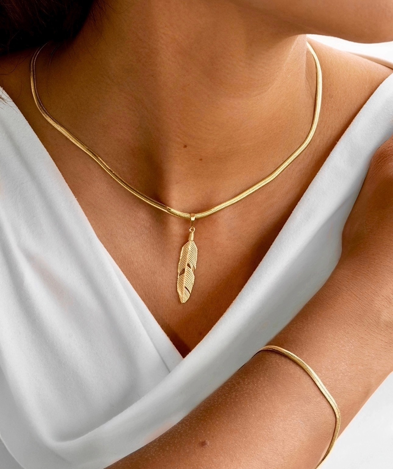 Zanjir-e Mari mit goldener Feder, getragen mit passendem Armreif – eleganter Look auf weißem Oberteil