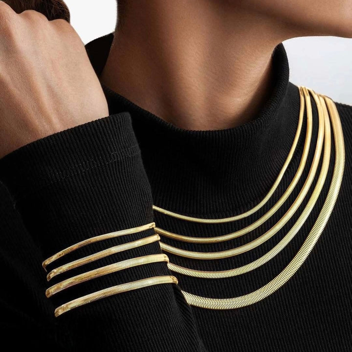 Mehrere Zanjir-e Mari Ketten und Armreifen aus 18k Gold – gestapelt getragen auf schwarzem Rollkragen