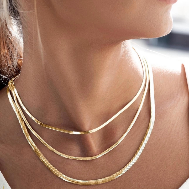Drei Schlangenketten aus 18k Gold – schlicht &amp; glänzend getragen auf heller Haut und weissem Top