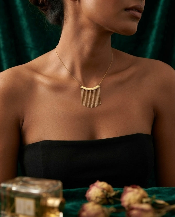 Model trägt eine filigrane Halskette aus 18k Gelbgold mit feinem Fransen-Anhänger vor elegantem dunkelgrünem Hintergrund – Ziba Gold Schmuck.