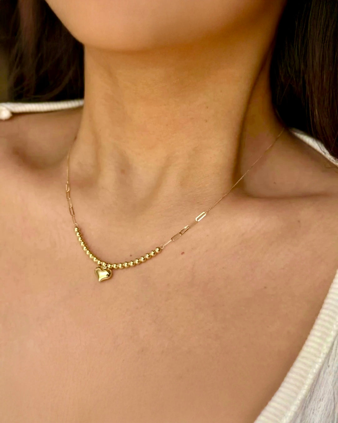 Zarte 18k-Gelbgold-Halskette mit fein polierten Goldkugeln und kleinem Herzanhänger, elegant am Hals getragen.