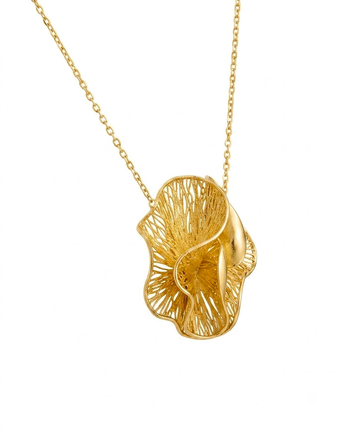 Elegante Halskette aus 18 Karat Gelbgold mit einem kunstvoll gearbeiteten, floralen Anhänger. Das organisch geschwungene Design kombiniert filigrane, durchbrochene Strukturen mit sanft polierten Goldflächen und erzeugt ein faszinierendes Spiel aus Licht und Schatten. Der moderne, skulpturale Anhänger hängt an einer feinen Ankerkette und wirkt gleichzeitig leicht, luxuriös und zeitlos – ein ausdrucksstarkes Schmuckstück für besondere Anlässe und den stilvollen Alltag.