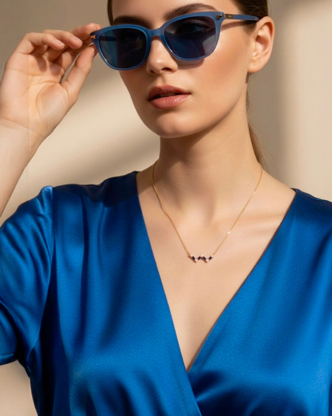 Elegante Frau mit Sonnenbrille trägt feine 18k Gelbgold-Halskette mit blauen Akzenten, minimalistischer Damenschmuck, stilvoll inszeniert