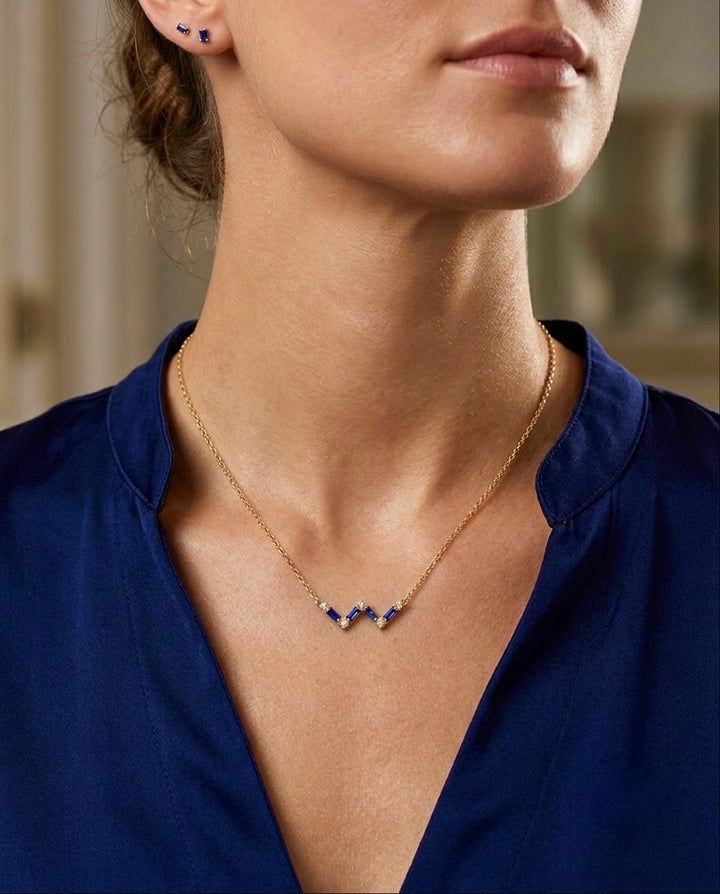 Elegante 18k Gelbgold-Halskette mit geometrischem Anhänger aus tiefblauen Steinen und funkelnden Akzenten, getragen als edles Schmuckset mit passenden Ohrsteckern.