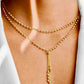 Elegante Y-Halskette aus 18 K Gelbgold mit feinen Goldkugeln, zweireihig gearbeitet und mit filigranem, herabhängendem Kettenelement, getragen am Hals einer Frau vor hellem Hintergrund.