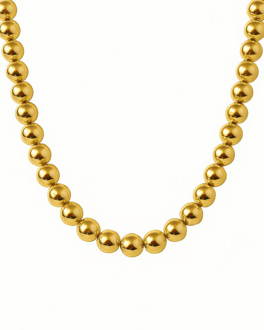 Detailaufnahme einer runden Goldperlenkette aus 18k Gelbgold, gleichmäßig kugelförmig gearbeitet, elegant und luxuriös