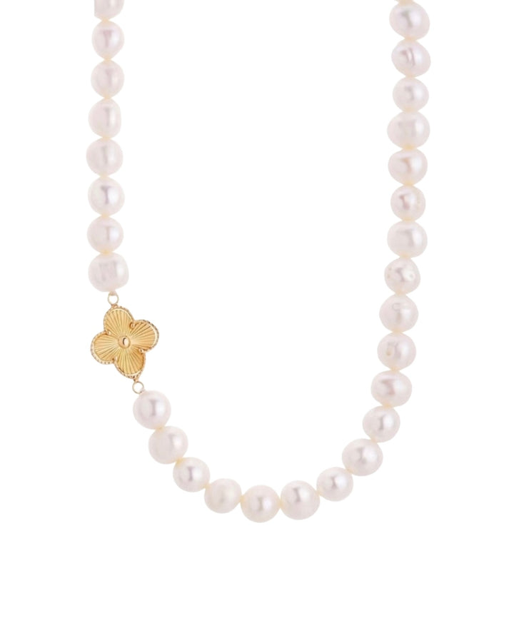 Detailaufnahme einer Halskette mit weissen Zuchtperlen und Kleeblatt aus 18k Gelbgold