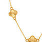 Detailaufnahme einer eleganten Halskette aus 18 Karat Gelbgold mit zwei filigran gestalteten Kleeblatt-Elementen. Die glänzenden Anhänger zeigen ein strahlenförmiges Muster mit feiner Perlenrand-Verzierung und sind durch eine zarte Goldkette verbunden. Der Schmuck ist vor hellem Hintergrund fotografiert und betont die hochwertige Verarbeitung sowie den warmen Goldglanz.