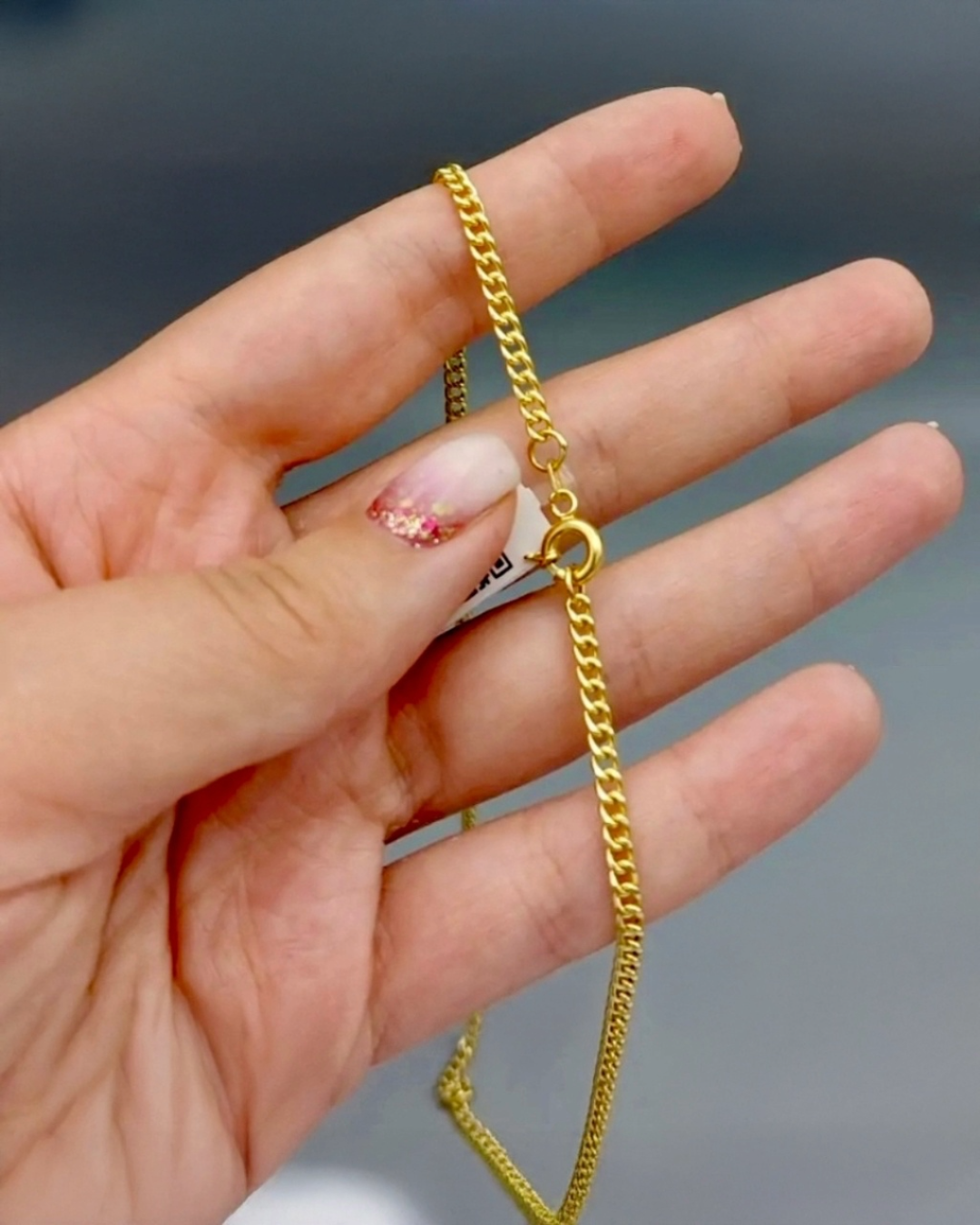 Detailaufnahme einer 18 Karat Gold Halskette mit klassischem federringverschluss und Panzerkette, hochwertiger handgefertigter Goldschmuck in der Hand gehalten.