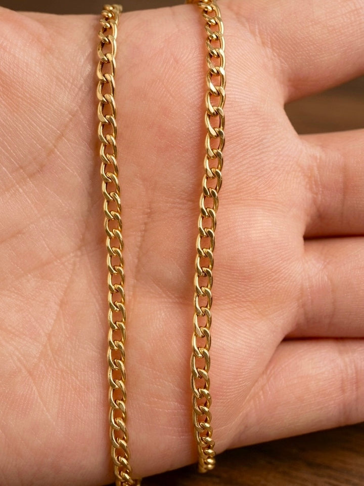 18 Karat Gelbgold Panzerkette in Nahaufnahme auf einer Handfläche – klassische, flach geschliffene Gliederkette mit hochglanzpolierter Oberfläche, zeitloses Design für Damen und Herren.