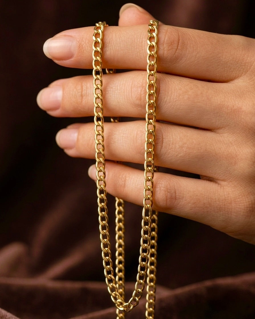 18 Karat Gelbgold Panzerkette elegant über einer Hand drapiert – klassische Gliederkette mit hochglanzpolierter Oberfläche, zeitloses Schmuckstück für Damen und Herren, ideal für den Alltag und besondere Anlässe.