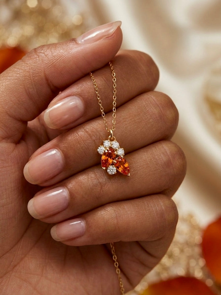 18 Karat Goldkette mit elegantem Anhänger aus orangefarbenen Navette-Steinen und funkelnden Zirkonia-Blüten, präsentiert an einer Hand – hochwertiger Damenschmuck von Ziba Gold.