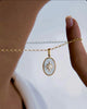 Nahaufnahme einer Halskette aus 18 Karat Gelbgold mit ovalem Anhänger – Perlmuttgrund und ein goldener Stern mit funkelndem Stein in der Mitte, elegant zwischen den Fingern gehalten und vor hellem Hintergrund präsentiert.