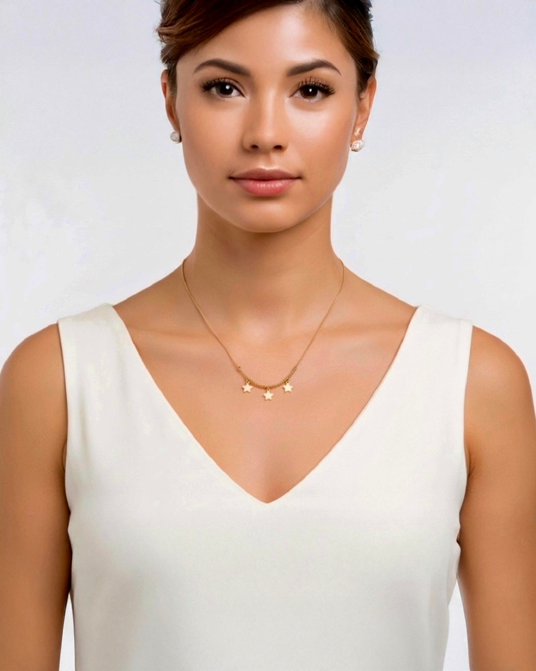 Feine 18k Gelbgold-Halskette mit drei Stern-Anhängern, minimalistisch getragen an zarter Goldkette, elegant kombiniert mit cremefarbenem Kleid.