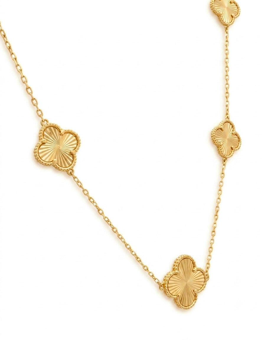 Detailaufnahme einer eleganten Halskette aus 18 Karat Gelbgold mit vierblättrigen Kleeblatt-Elementen. Die fein gearbeiteten Kleeblätter mit satinierter Oberfläche und strahlenförmiger Gravur sind harmonisch entlang der filigranen Ankerkette angeordnet und verleihen der Goldkette einen zeitlosen, luxuriösen Look – hochwertiger Damenschmuck für jeden Anlass.