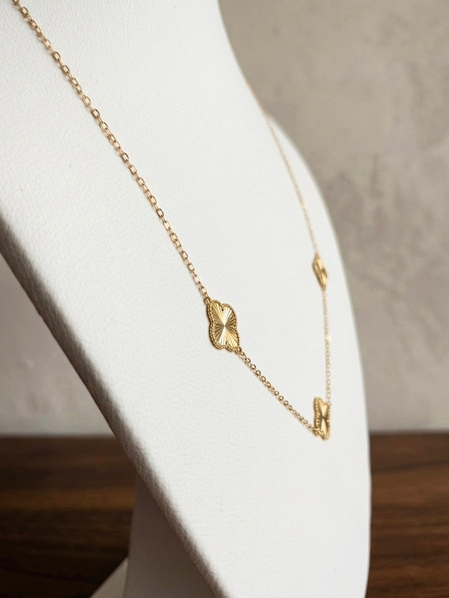 Filigrane Halskette aus 18k Gelbgold mit drei diamantierten Kleeblättern auf einer Schmuckbüste.