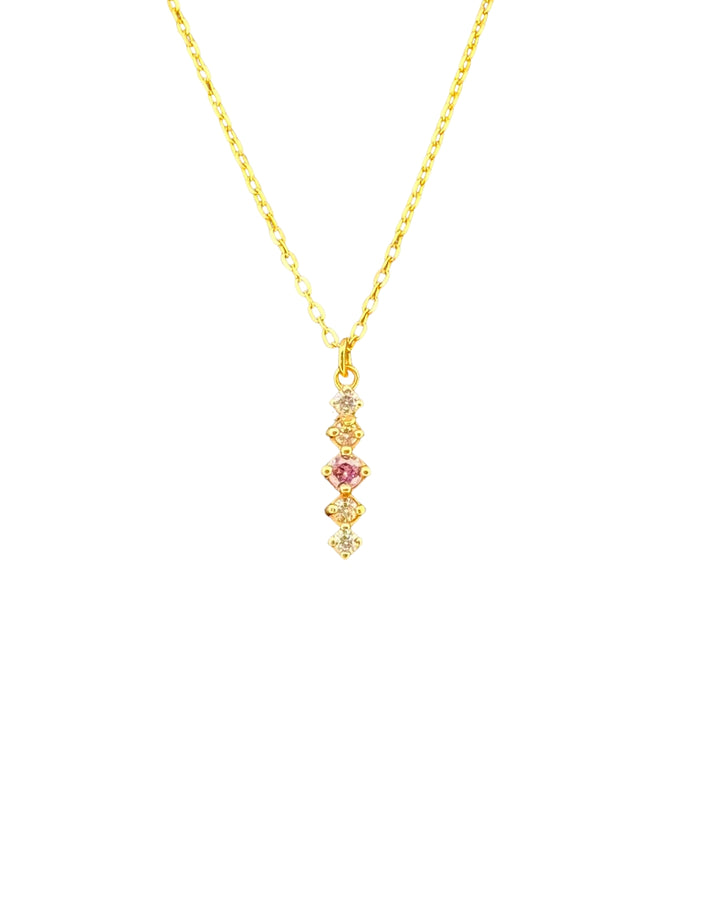 Vertikaler Anhänger mit mittlerem pastellvioletten Zirkonia, sanft rosiger Schimmer, flankiert von klaren Steinen – gefasst in 18k Gelbgold, auf weissem Hintergrund.