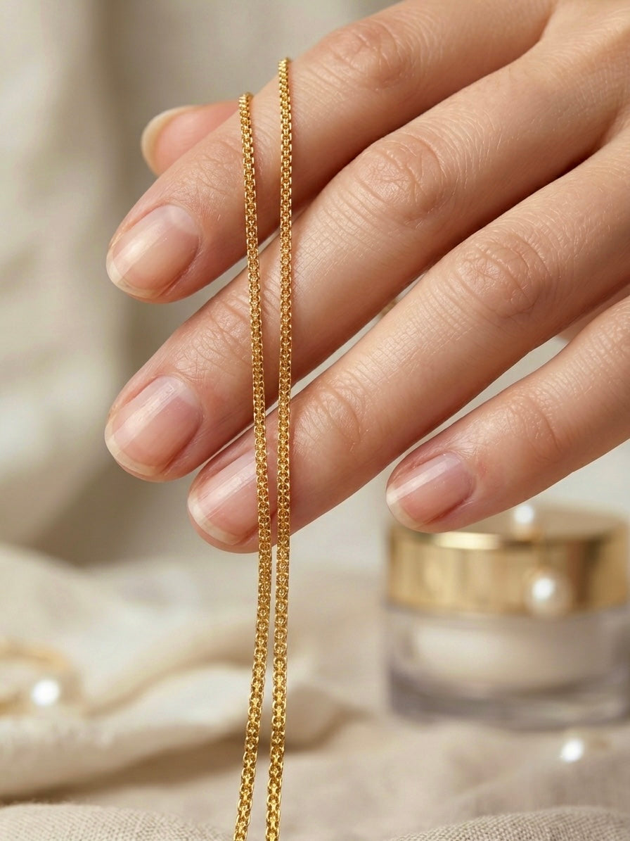 Feine Halskette aus 18 Karat Gelbgold mit filigraner Kettenstruktur, elegant über einer Hand präsentiert.