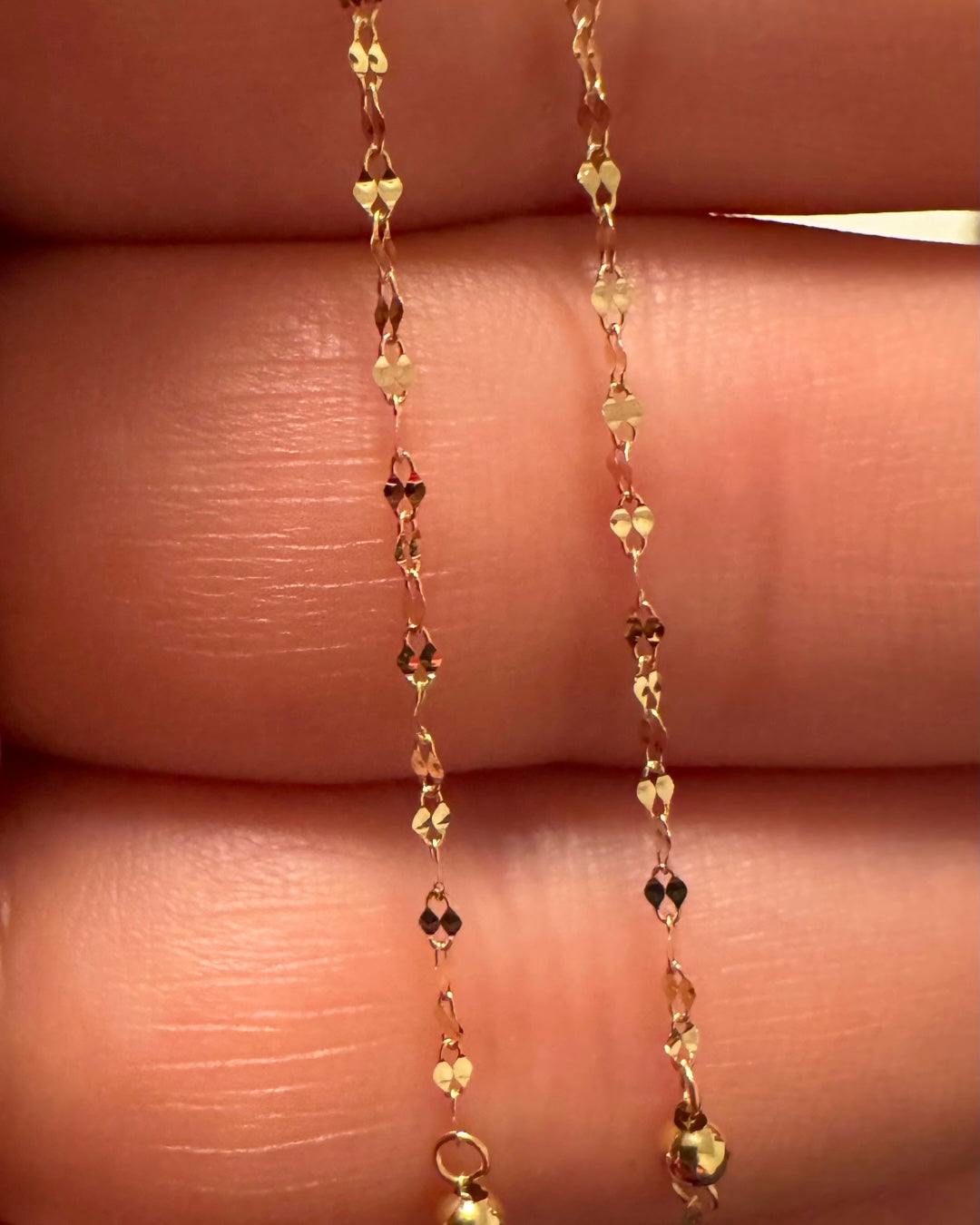 Detailaufnahme einer 18k Gelbgold Halskette mit 1 cm ovalen Gliedern und 2 mm Goldkugeln – feine 1 mm Strukturkette in Nahansicht