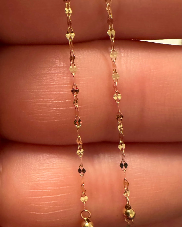 Detailaufnahme einer 18k Gelbgold Halskette mit 1 cm ovalen Gliedern und 2 mm Goldkugeln – feine 1 mm Strukturkette in Nahansicht