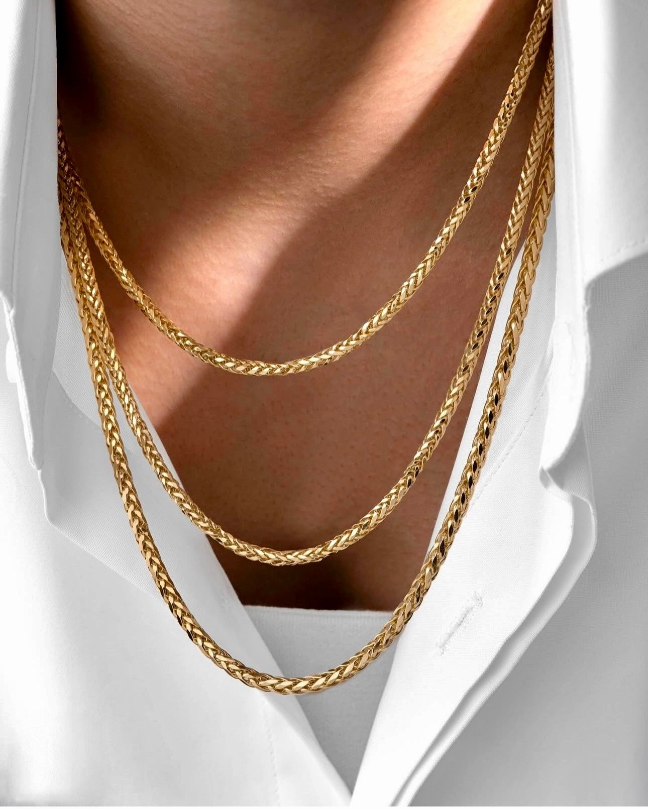 Halskette aus 18k Gelbgold – Zanjir-e Miro-ye Bosorg (Grosse Mirokette). Mehrlagige, massive Miro-Ketten in glänzendem Gold, getragen über einem weißen Hemd.